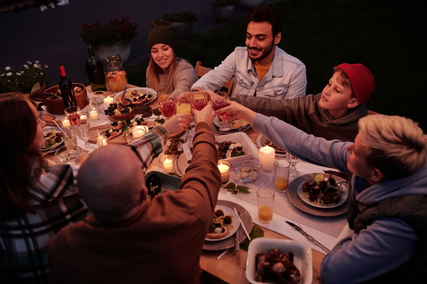 Parents and children raising a toast at a candlelit outdoor dinner